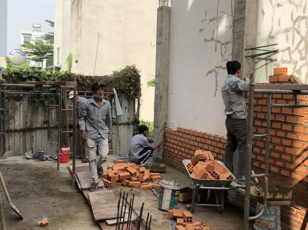 Công nhân đang căng dây lèo và búng mực trên nền sàn bê tông, chuẩn bị xây dựng tường gạch thẳng.