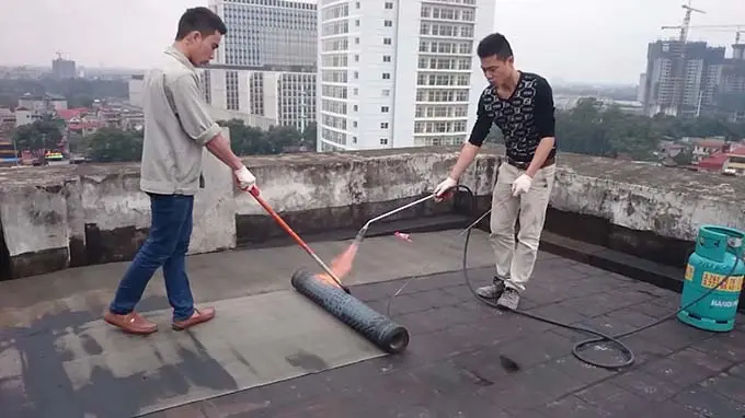 Hình ảnh thi công màng chống thấm bitum khò nóng trên bề mặt sàn mái công trình.