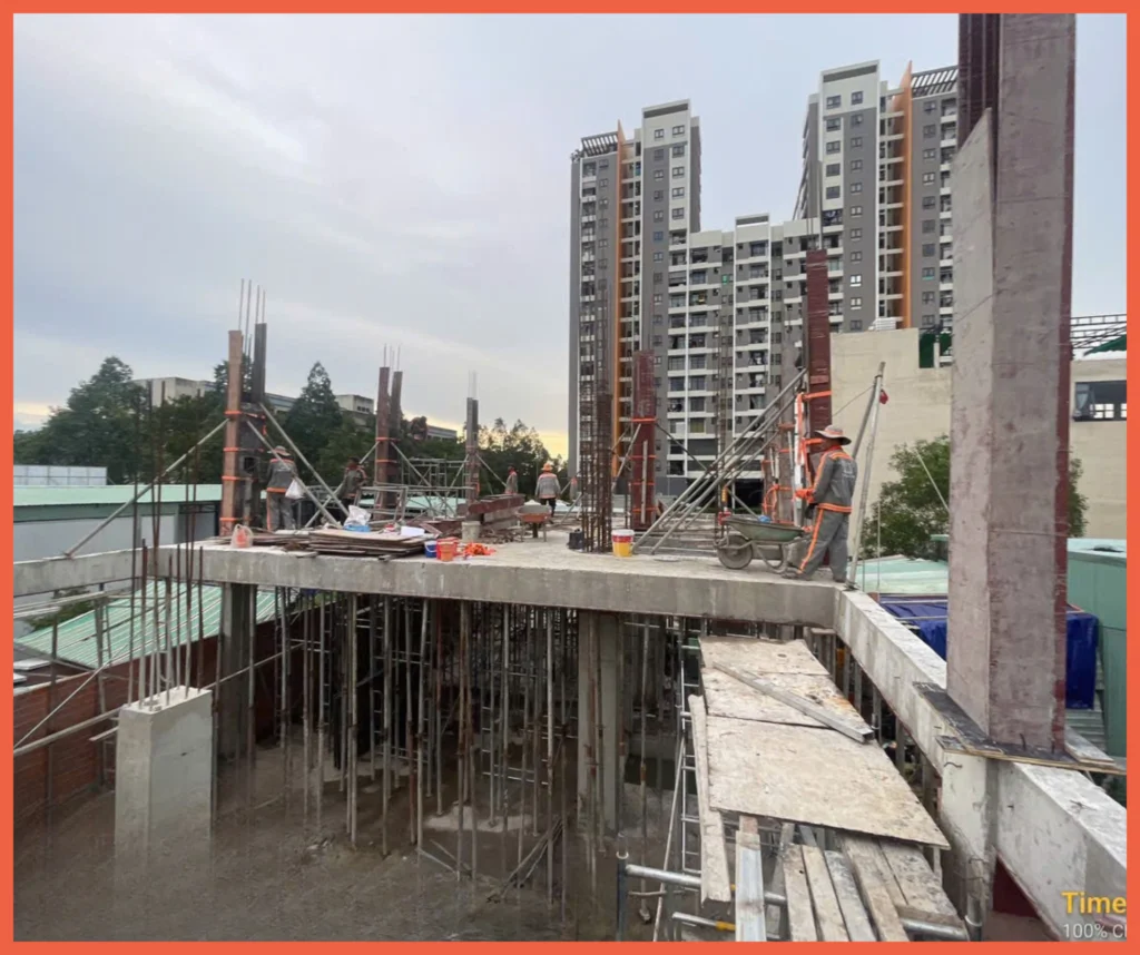 Công nhân đang đổ bê tông vào cốp pha cột nhà, tuân thủ quy trình kỹ thuật để đạt chất lượng cao.