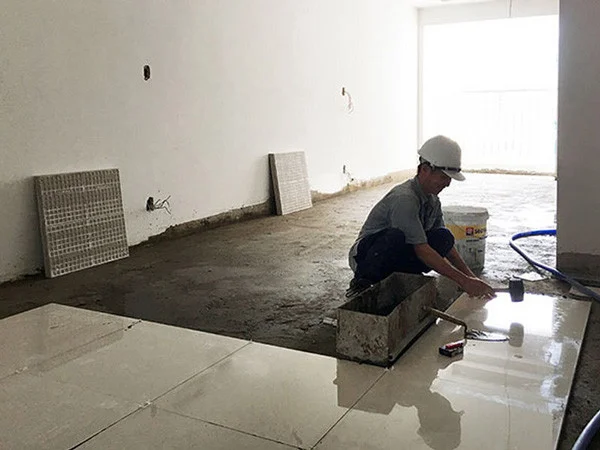 Công nhân đang chuẩn bị lớp nền cơ sở bằng vữa xi măng cát để lát gạch nền.