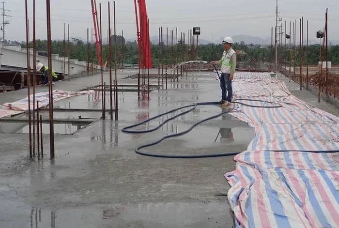 Công nhân thi công đổ và đầm bê tông sàn mái theo các bước kỹ thuật, đảm bảo kết cấu vững chắc.